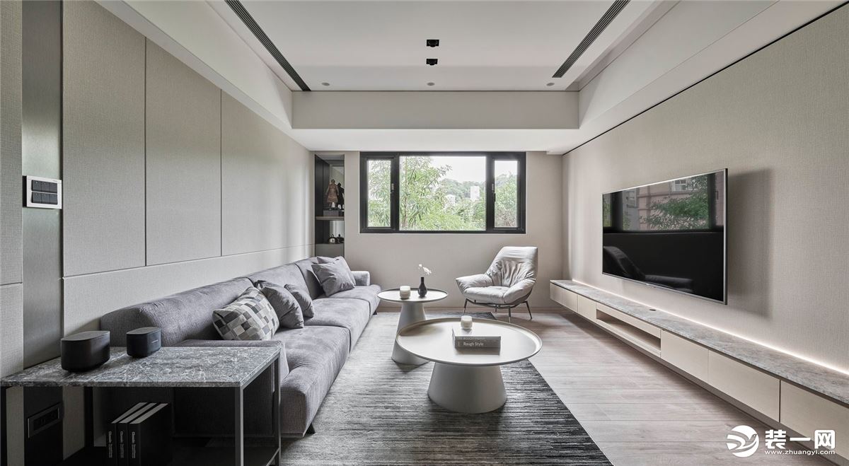 客厅以米色作为背景色，浅灰色的布艺沙发搭配地毯，大小不一的圆形茶几，时尚简单，电视柜的与沙发旁的收纳
