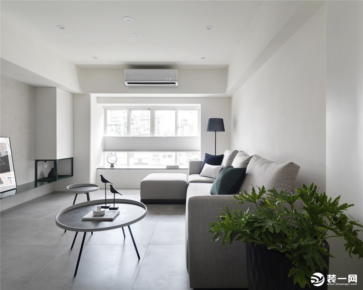 客厅以白色作为主色，浅色系的设计，灰色的沙发搭配上大小不一的组合茶几，沙发旁的绿植，简单自然