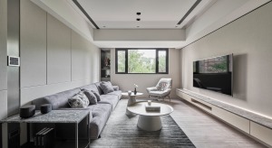 客厅以米色作为背景色，浅灰色的布艺沙发搭配地毯，大小不一的圆形茶几，时尚简单，电视柜的与沙发旁的收纳