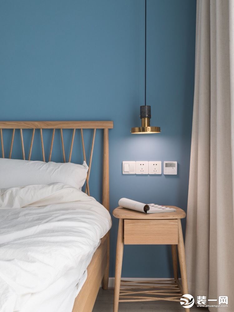 卧室：蓝色墙面与木质床具的搭配十分和谐，黄铜吊灯线条利落，整个空间利落静谧。