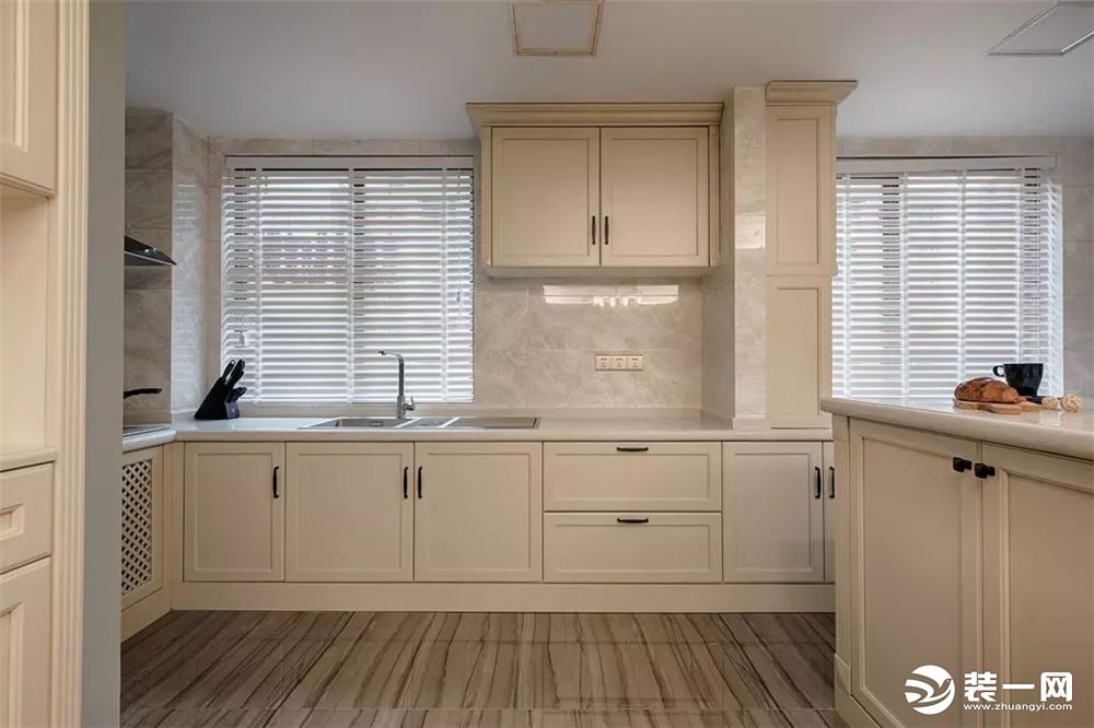 厨房采用浅色仿石纹瓷砖铺贴背景，搭配白色橱柜，整体干净整洁。