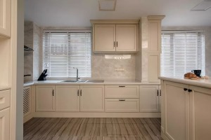 廚房采用淺色仿石紋瓷磚鋪貼背景，搭配白色櫥柜，整體干凈整潔。