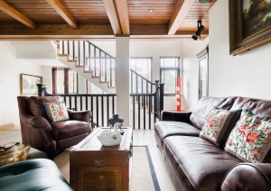 开放式起居室选用美式皮沙发，复古祖母绿和高级棕红色形成色彩反差，在浅色地板映衬下，高级感倍升。