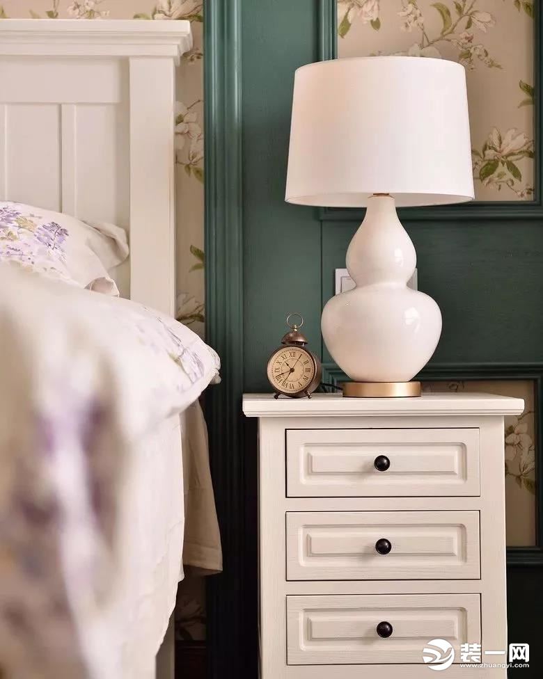 床头旁边的抽屉床头柜，还有一只葫芦造型的台灯，一只复古闹钟，精致的细节让房子充满了优雅的气息。