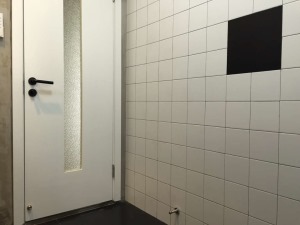 卫生间的墙面用素白小砖，配一片黑色砖。地面也是纯黑色搭配
