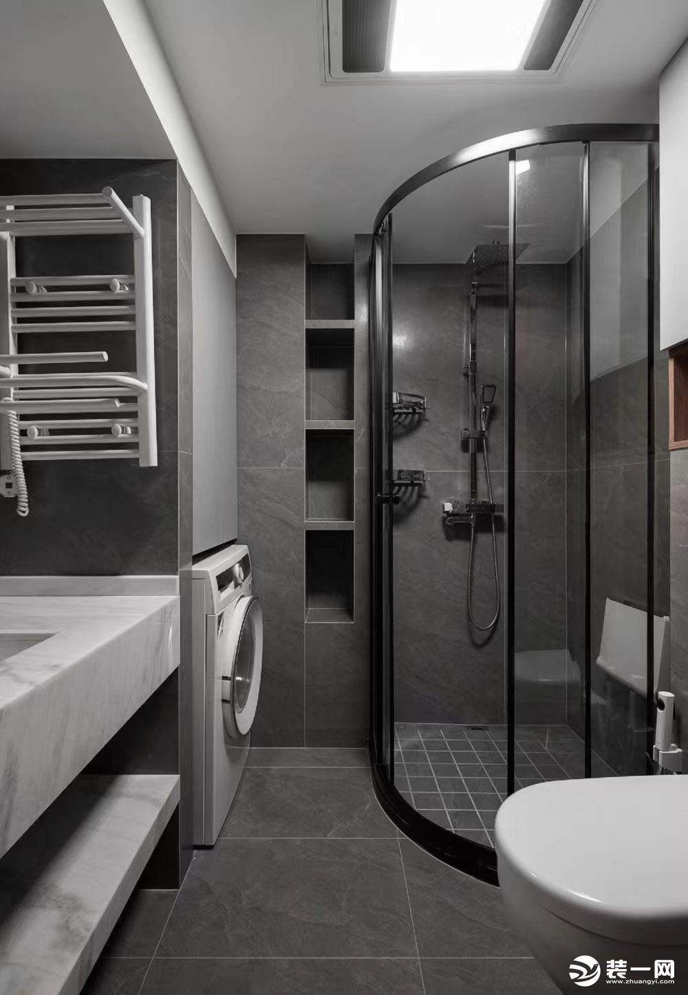 衛生間以黑白灰為主色調，淋浴區選擇弧形的玻璃，相對來說比較節約空間。洗漱臺分成兩層，下層直接是設計的