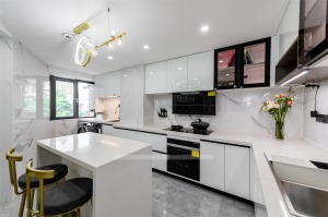 台面超薄纯白岩板延伸至墙面，做到一个挡水的作用，纯白与黑色的抽油烟机，打造出黑白配极简的厨房。