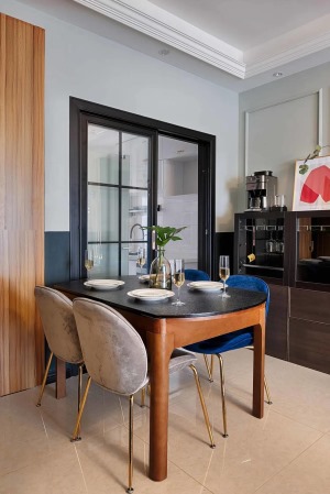 餐廳與廚房之間裝上黑框玻璃推拉門，而餐桌也是實木框架+石材臺面的組合，搭配上輕奢精致的餐椅，還有后方