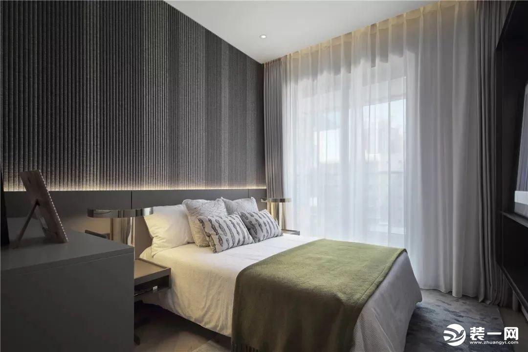 卧室的床头墙以波纹软包为背景，墙脚位置装了带灯带的护墙板，布置简约现代的床单，营造出一种华丽自然的舒