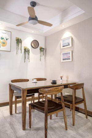 餐厅的墙面干净简洁，一面是挂上装饰画、另一面则是挂着独特的绿植墙饰与挂钟，在筒灯的烘托下呈现出一种独