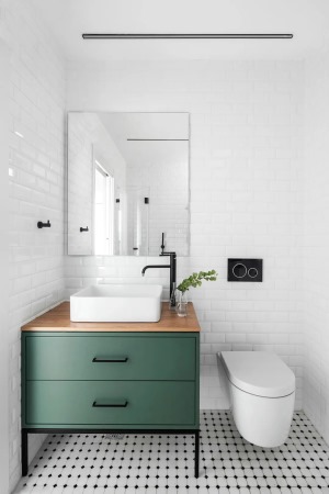 次卫整体白色地砖加入黑色的圆点，布置墨绿色浴室柜，台上盆的设计与整体白色墙面相呼应，使得卫浴空间充满