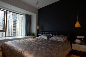 卧室背景墙整体刷成黑色，搭配两侧吊灯设计暖意融融。