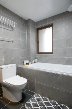 卫生间整体用暗色瓷砖铺贴，暗色调耐脏，靠墙位置设计了浴缸+淋浴组合，幸福指数大大提升。