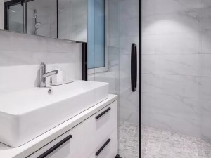 卫生间，浅色空间加入黑色线形把手点缀，镜柜与抽拉龙头方便实用，黑框玻璃移门划分出淋浴空间