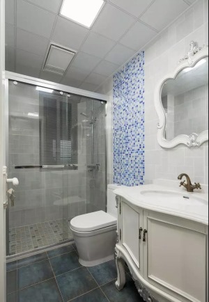  卫生间以灰白两色为主调，深灰蓝地砖营造宁静而幽然的氛围，墙面局部点缀蓝色系马赛克瓷砖，带入活力与悦