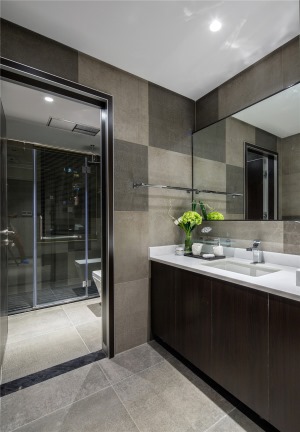 卫生间以灰色瓷砖为主，搭配白色洁具，及深色浴室柜，让卫生间也能有丰富的层次感