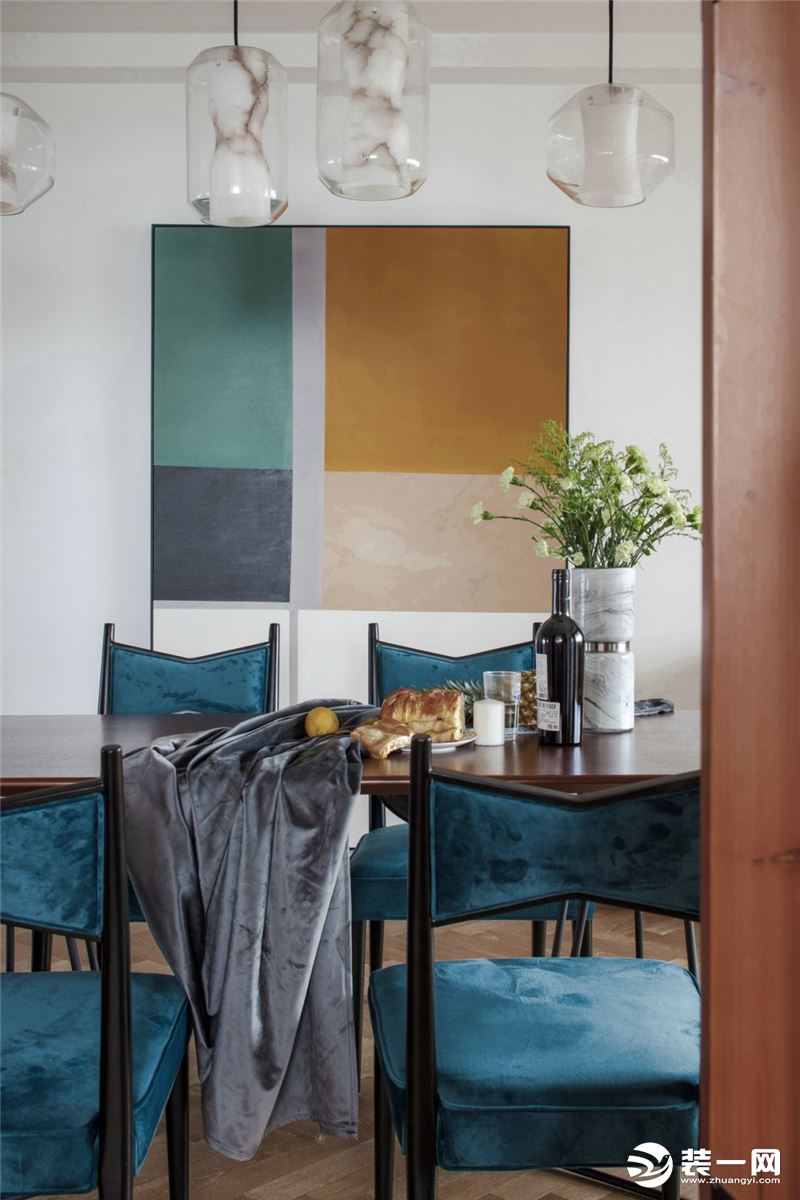 蓝色绒布餐椅和黄色装饰画，与客厅的软装配色相呼应