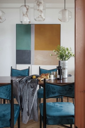 蓝色绒布餐椅和黄色装饰画，与客厅的软装配色相呼应