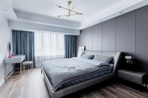 整个主卧的灰色调里，用蓝色窗帘点缀。 深灰色饰面作为床头背景，同色系的撞色，更显空间的质感和档次。