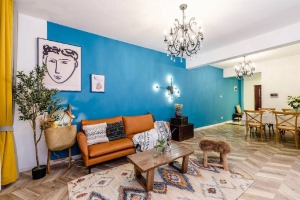 沙发墙面采用的深蓝色墙漆与白漆搭配的方式，配上欧式复古水晶吊灯，皮草矮凳，原木茶几，皮质沙发。
