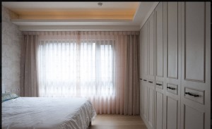 主卧墙面柜收纳强大，没有复杂的装饰，浅粉的窗帘让家更加有了温馨的氛围。