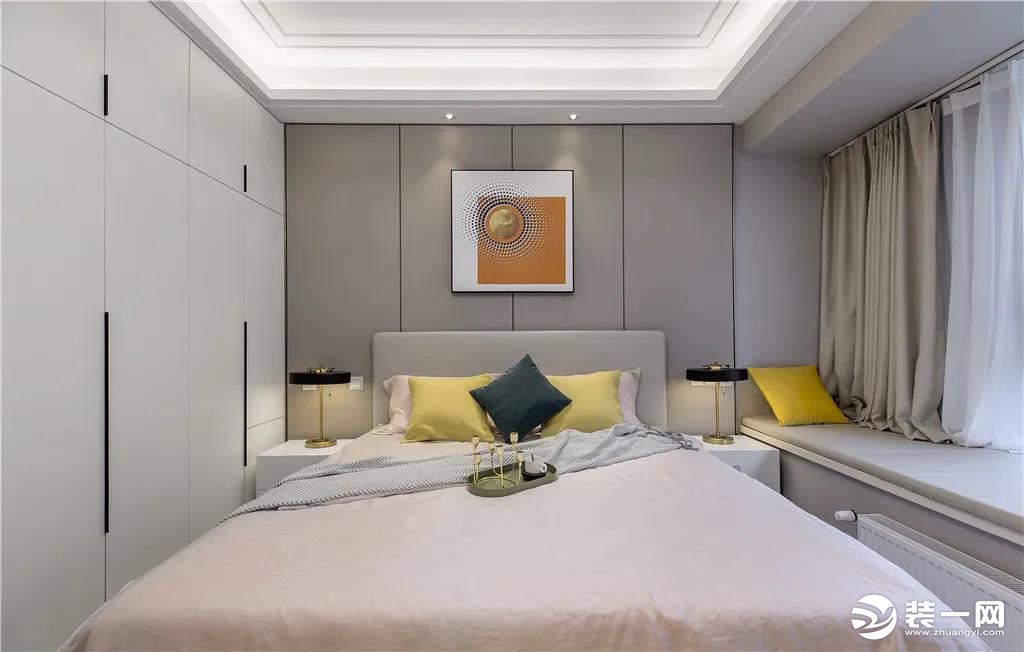 主人房在床头墙以硬包背景墙的基础，布置皮质的床铺，粉色的床单与黄色枕头布置，还有环形的灯具，让睡眠空