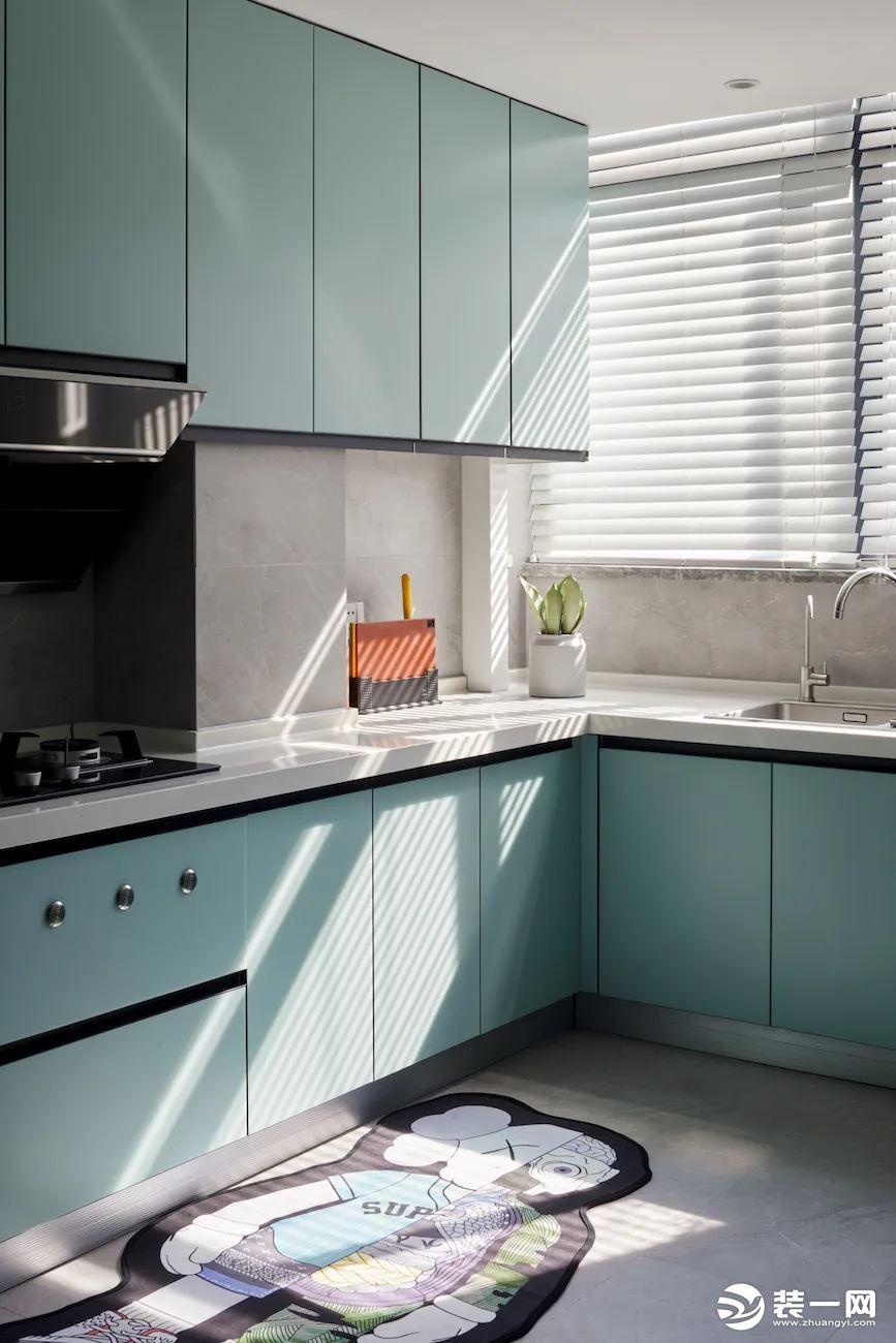 厨房地面垫上一块二次元风格的地毯，灰色地砖与墙砖结合淡蓝色的定制橱柜，让做饭空间也充满清新与自然的舒