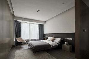 卧室在无主灯的空间基础，床头墙以深色墙脚+白色墙身的层次感下，布置舒适的灰色床铺，呈现出一种舒适自然