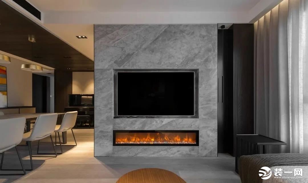  电视墙采用银灰色石材，内嵌式壁挂电视，下方的仿真燃烧壁炉在冷色调的背景中平衡暖意。