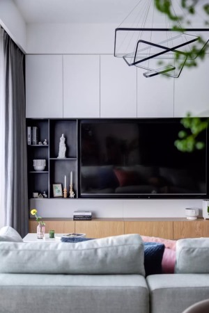 电视墙以定制柜作为主体，左侧加入了几个黑色的开放格架，摆上雅致的装饰品，让空间显得现代优雅而大气。