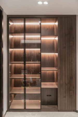 走廊位置装了一个带有玻璃门+开放格的收纳展示柜，木色的设计，在每层柜子都加入了灯带，使得柜子内部更加