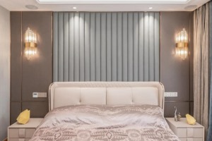 卧室床头墙以硬包+软包结合的背景墙设计，中间波纹造型的软装，两侧是卡其色的硬包背景，结合金属线条与壁