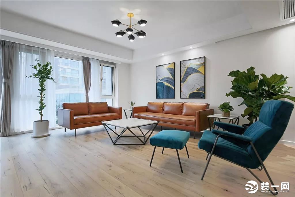 客厅整体简洁现代的空间，搭配上驼色的皮沙发布置，沙发墙挂着两幅轻奢风格的装饰画，让空间充满意韵优雅