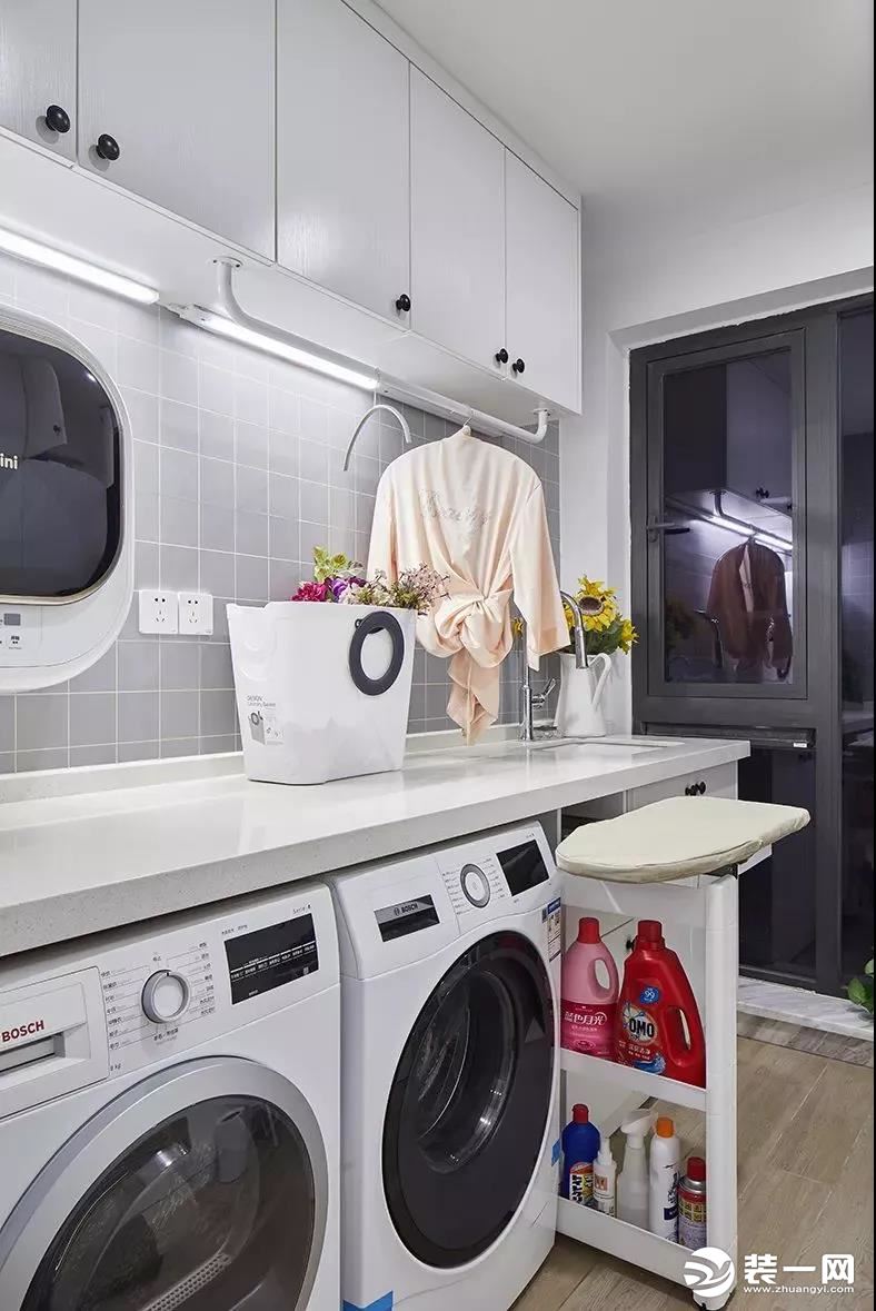 在入户玄关的侧面是有着一个独立的洗衣房，洗衣机、烘干机和柜子的结合，移动小推车上还方便熨烫衣服