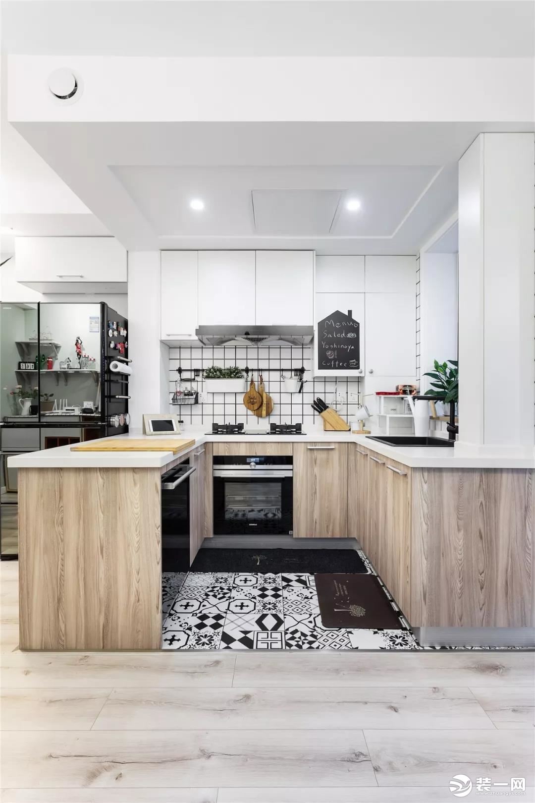  厨房地面铺设黑白马赛克地砖，墙面铺贴小块白色瓷砖，搭配木纹柜台和宜家风格的餐具