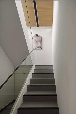 通往二楼的楼梯用了玻璃扶手护栏搭配灰色的踏步，在楼梯的底部做上了储物柜，避免了造成卫生死角