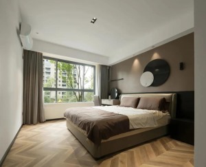 卧室床头墙是灰褐色的，挂上黑白配的圆形墙饰，布置上皮质的软质床，床头旁边还有一个梳妆台