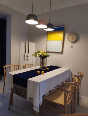 结合墙面的黄蓝白挂画，马卡龙色调的吊灯，让空间充满了活力，随时都能为家人提供一场浪漫温馨的晚宴。
