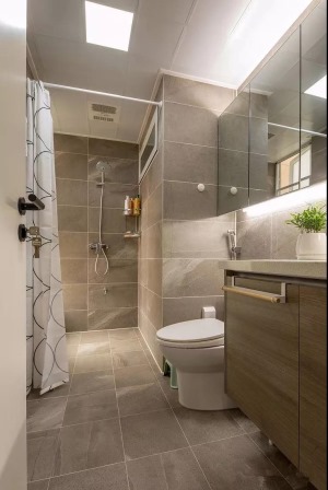 卫生间内部用浴帘来分隔了淋浴区，通体铺贴灰色调的瓷砖，搭配白色的卫具和木质感，让人感觉简洁而又轻松。