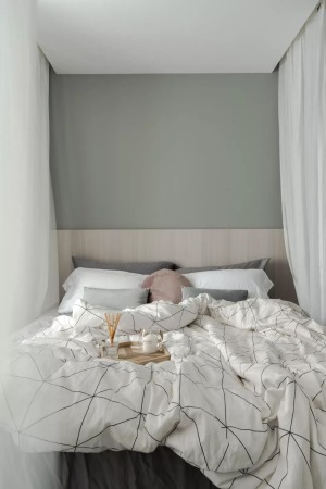 床头墙是暗绿色的空间，在天花里面藏了窗帘盒作为床帘，木质床头靠背，布置现代简雅的床单被套