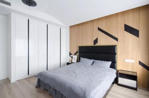 主卧室的床头背景墙选择了木色的饰面板设计，上方还点缀了部分的黑色长方块，带来更加别致的感觉。