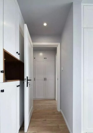 通往卧室的走廊过道也没有被浪费，设计师选择了嵌入式的白色柜子来增强收纳能力，白色与灰色的结合也显得简