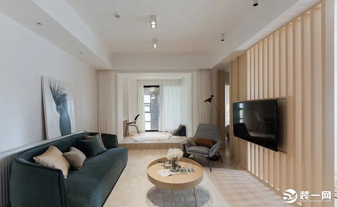 客厅整体以纯净的白墙+自然的木质为基调，蓝丝绒沙发优雅而高级，作为深色稳住空间气场。单人沙发椅千鸟格