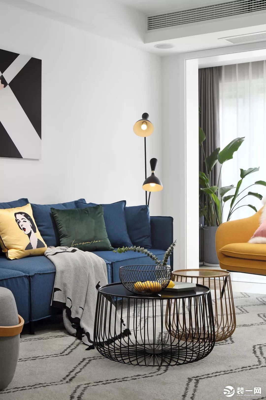 客厅选择了两张一黑一黄的底部镂空茶几，视觉上显得特别的轻松，蓝色沙发、黄色单椅和灰色地毯的结合，品位