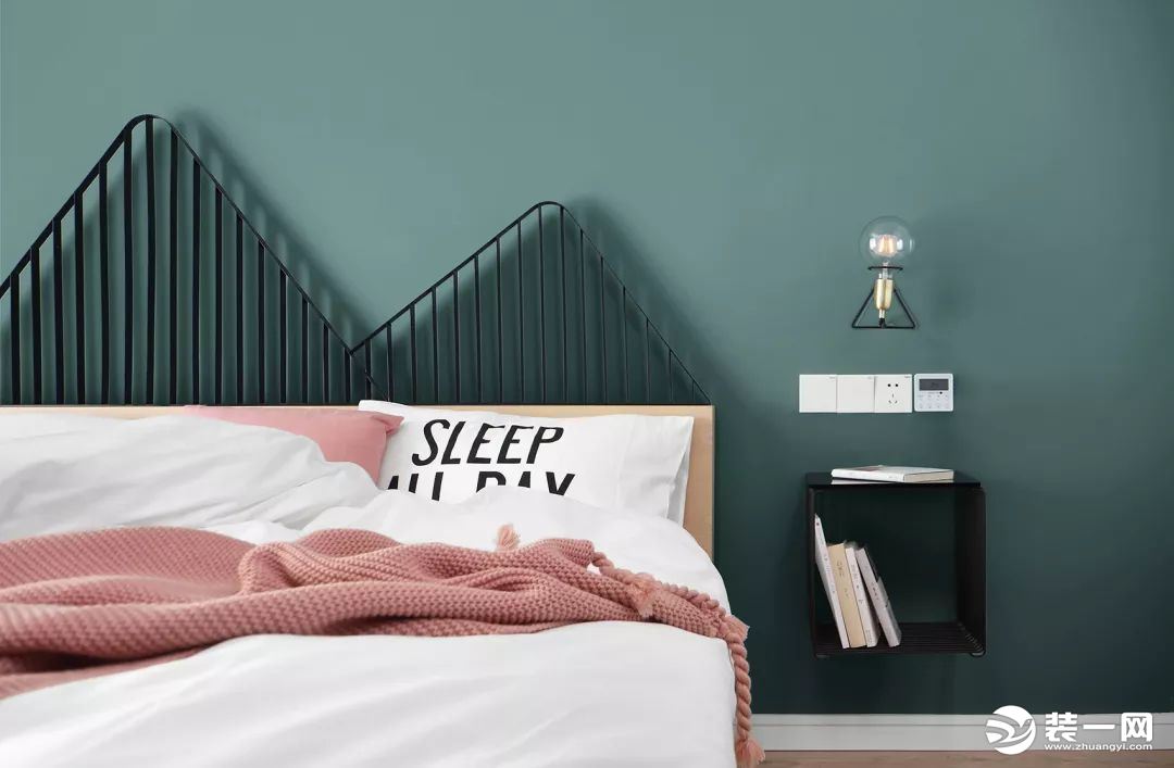 次卧的设计就更具趣味和创意了，墨绿色的背景墙，山体造型的铁艺床头靠背，床头柜是悬空的格子，壁灯的造型