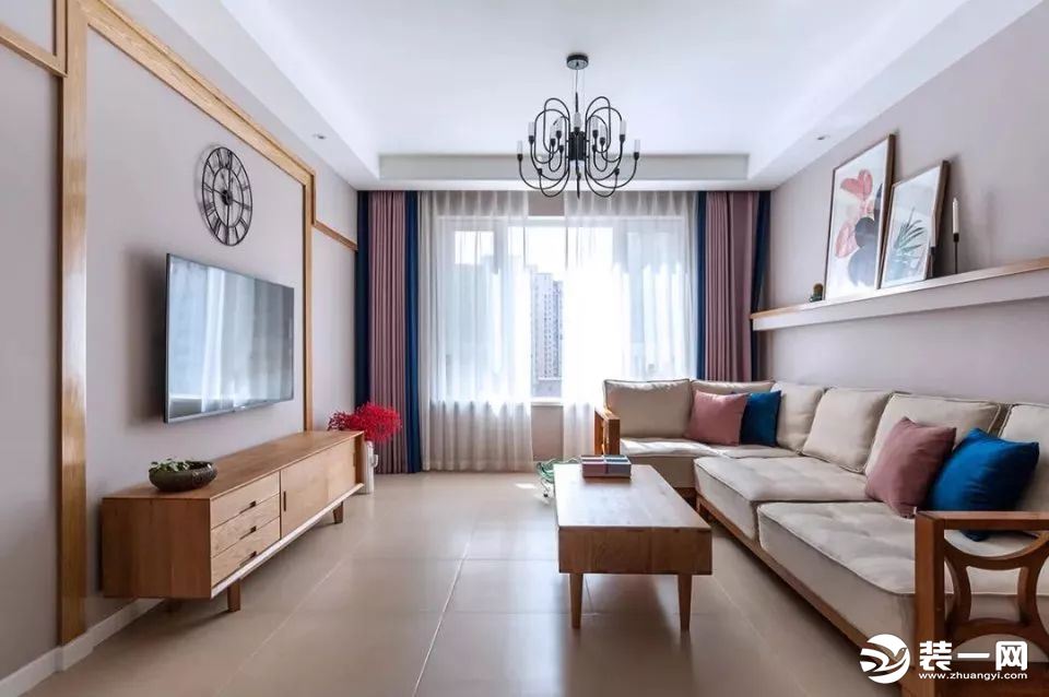 客厅，整体以白色与原木色为主，搭配浅粉和宝蓝色的窗帘与抱枕，赋予了空间满满的格调。电视墙采用线条感十