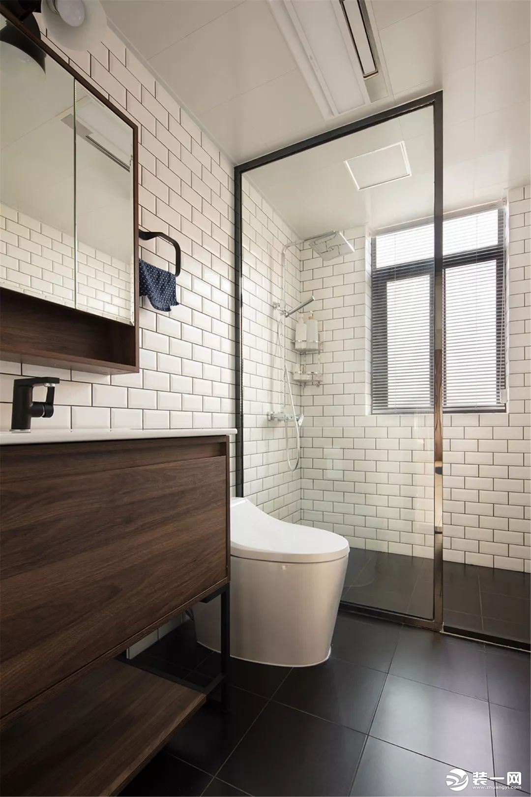 卫生间内部做了干湿分离的设计，淋浴房、马桶和洗手台呈一字形布局，深灰色、白色加上木色的设计，看起来简