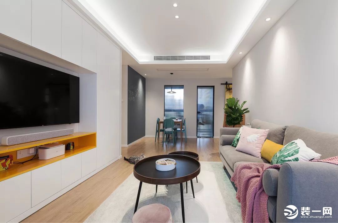 简洁舒适的客厅，电视墙是以定制柜的设计，电视机下方还加入了一排橙色的的展示架，让简洁的电视墙显得更加