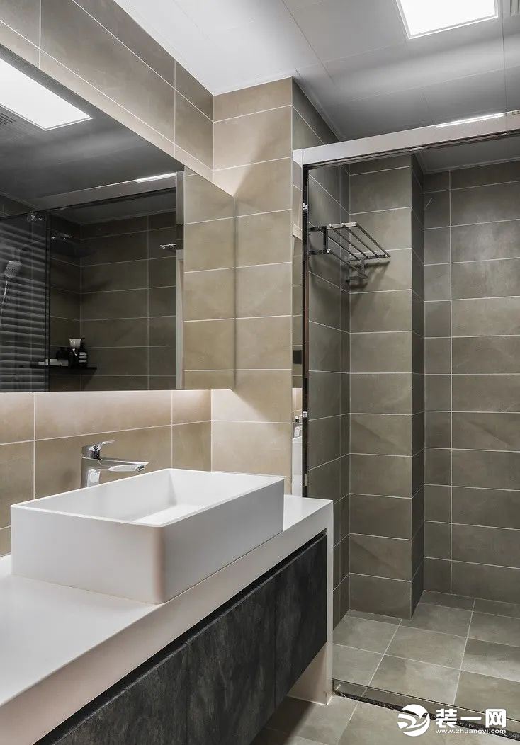 卫生间墙地面铺设灰色系瓷砖，搭配丰富的灯光设置及大面积的镜柜，使整体显得简约而富有质感。
