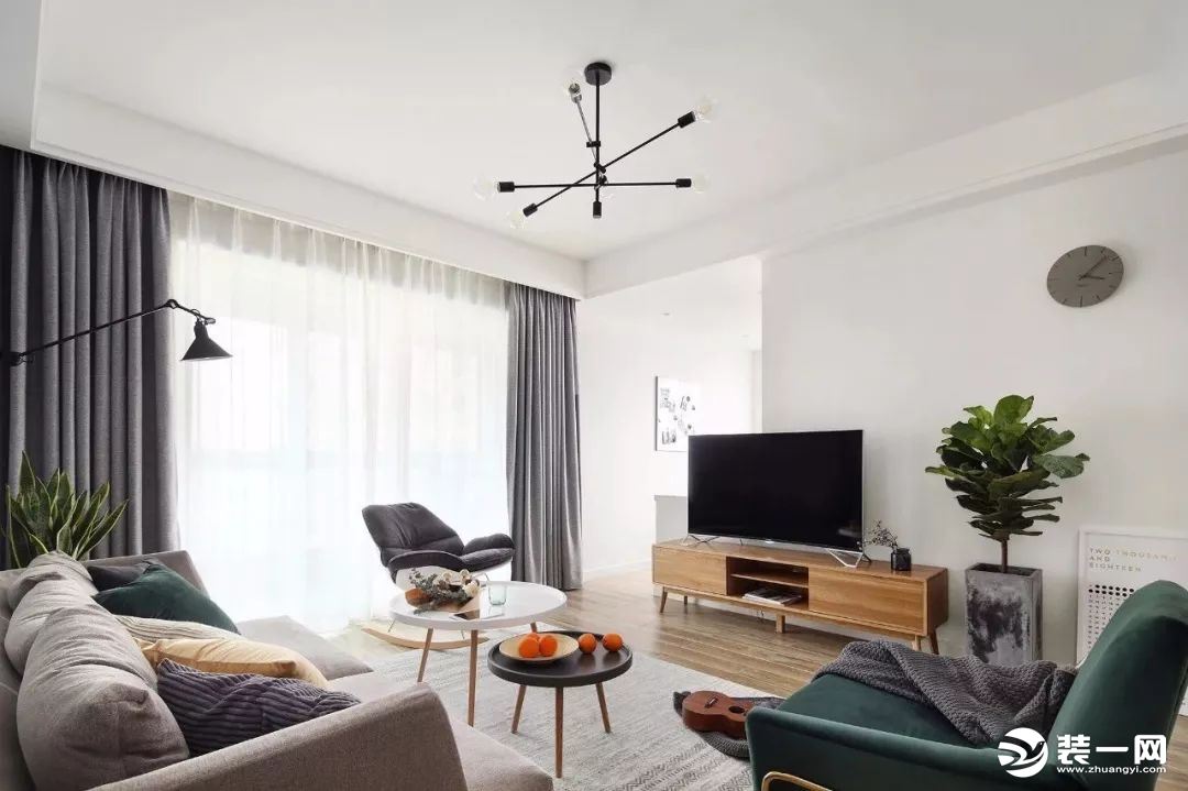 客厅地面通铺木地板，灰色沙发墙搭配灰色沙发、地毯，墨绿色单人椅作为点缀，非常吸睛。黑色铁艺杂志架，在